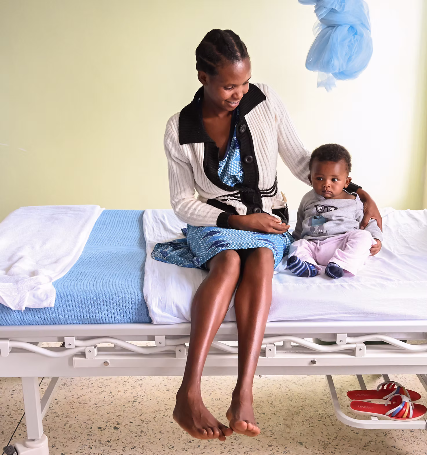 Fistula survivor on hospital bed hugging baby son