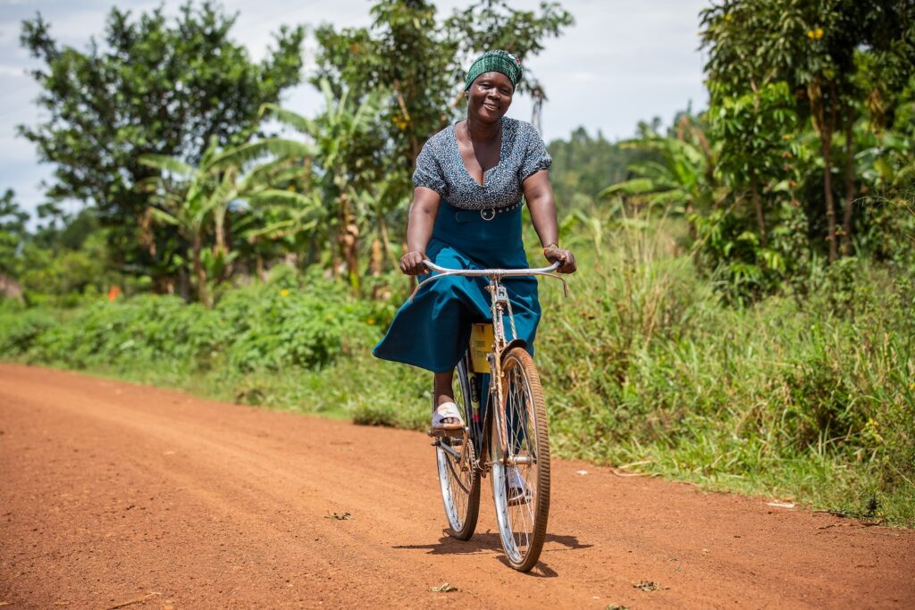 Woman riding a bike on a dirt road.