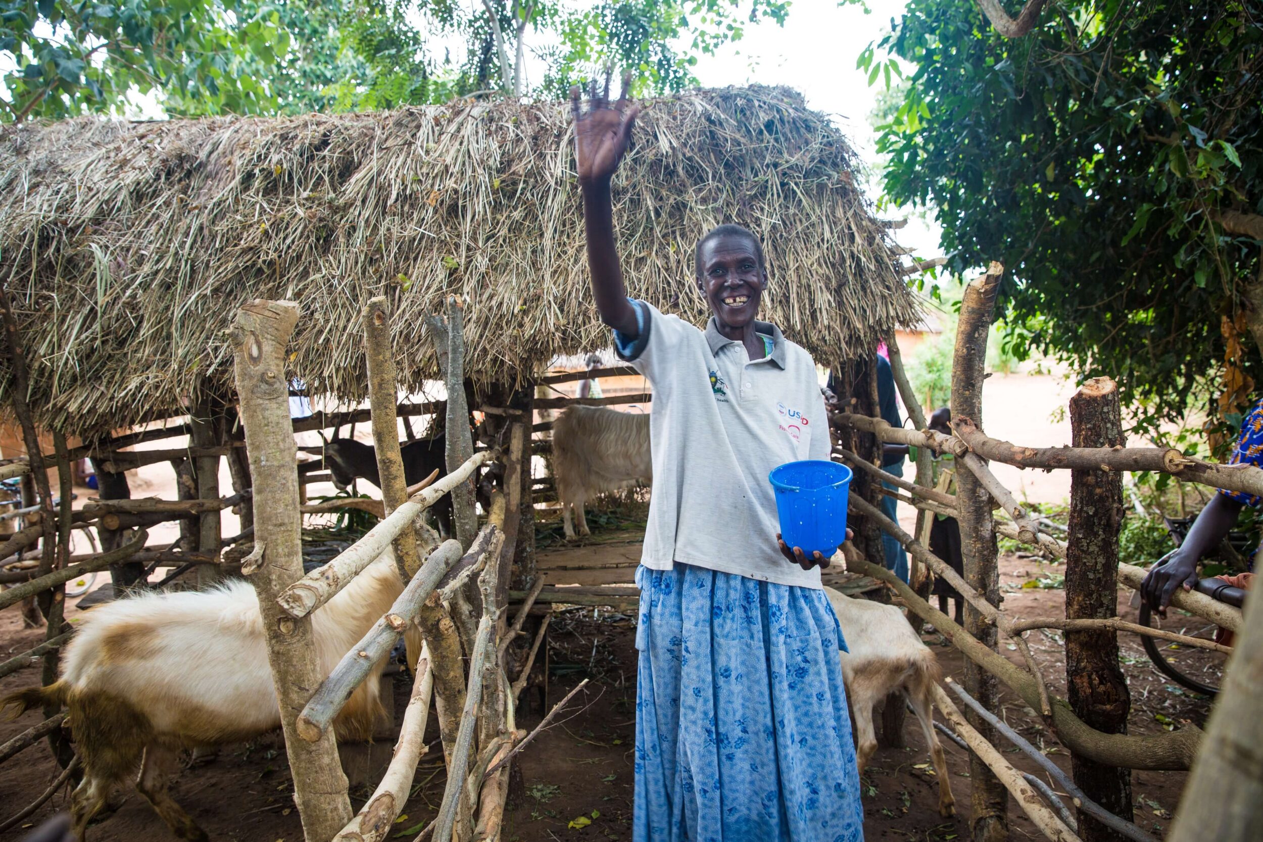Woman waving beside goats during community fistula recovery program