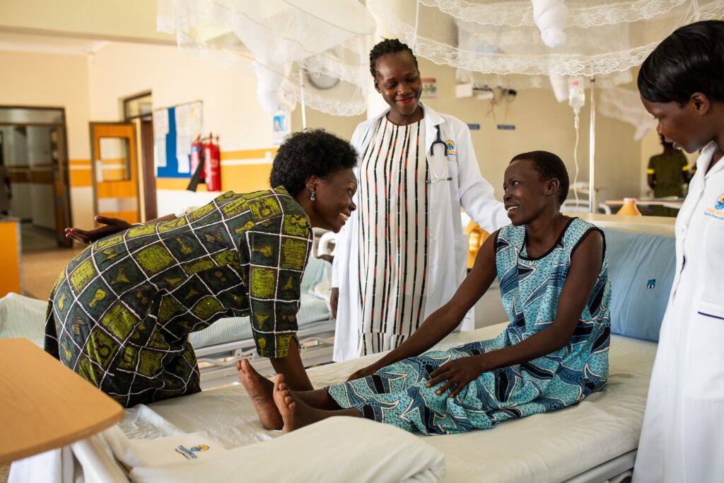 Alice, Dr. Mary, Agnes Fistula survivor talking to doctors in hospital bed